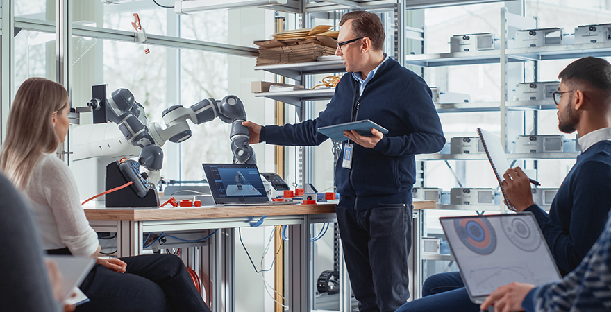 Profesor ingeniero dando clases de tecnología robótica e inteligencia artificial a trabajadores para automatizar los procesos de producción.