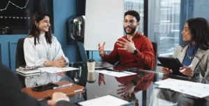 Grupo de empleados o equipo de finanzas reunido en una sala de la oficina debatiendo los beneficios o un informe económico de la empresa.