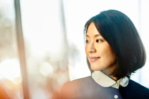 Portrait of a woman with a bob haircut looking to the right in a bright, softly lit setting.